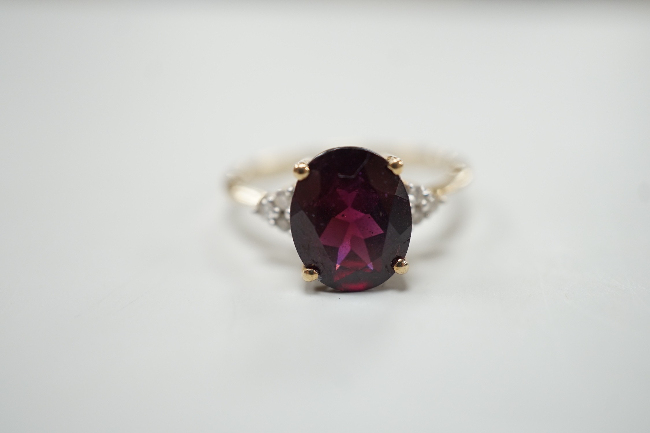 A modern 9ct gold, single stone oval cut garnet and six stone diamond chip set dress ring, size R/S, gross weight 2.8 grams.